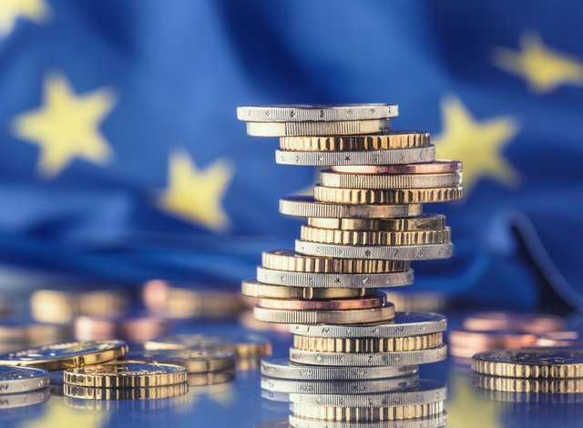 Tower with euro coins and flag of European Union in the background.