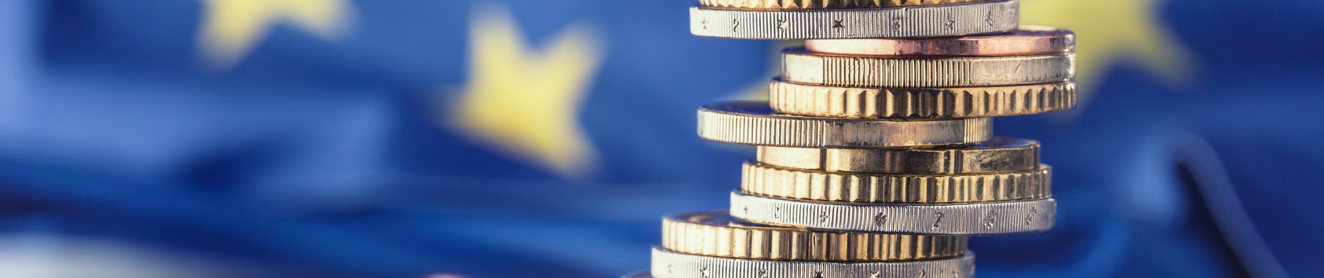 Tower with euro coins and flag of European Union in the background.