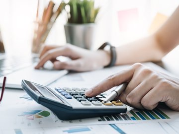 Close up Business woman using calculator and laptop for do math finance on wooden desk in office and business working background, tax, accounting, statistics