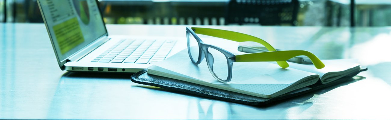 Laptop in the open air and green glasses on the keyboard